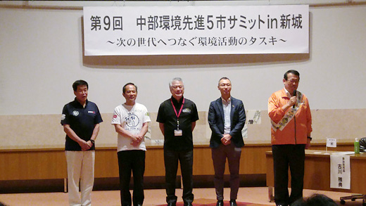 穂積新城市長(中央)からタスキを受け取り挨拶をする牧野飯田市長(右)