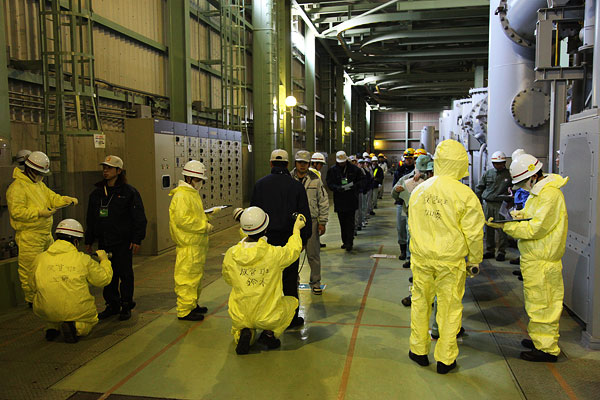 発電所構内の50万Ｖ開閉所で、退避する現場作業員の汚染レベルをサーベイメーターで測定する訓練の様子の写真